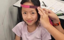 A student getting their head measured with a measuring tape
